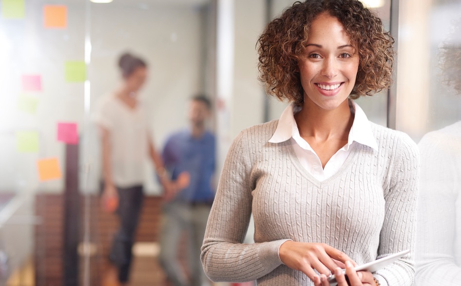 Professional woman in a sweater and collared shirt holding an iPad in an office