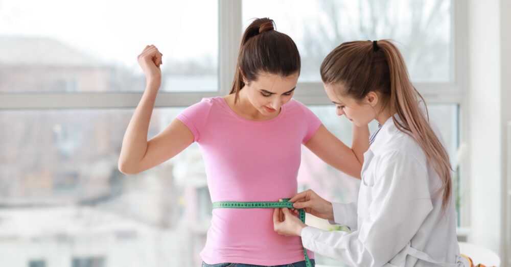 Provider assessing a woman’s weight loss progress